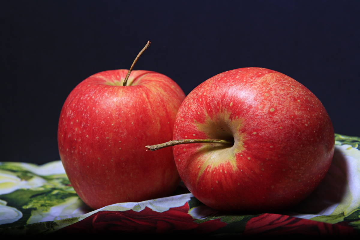 Two red apples on black background